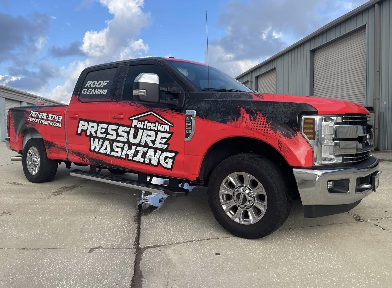 Perfection Pressure Washing red and black wrapped truck and equipment trailer parked on a job site